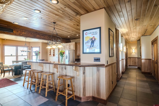 bar featuring wooden ceiling, stainless steel refrigerator with ice dispenser, dark tile patterned floors, and hanging light fixtures