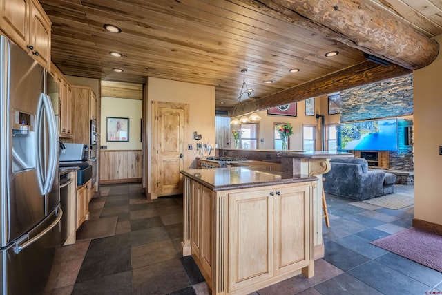 kitchen featuring light brown cabinetry, wood ceiling, appliances with stainless steel finishes, dark tile patterned floors, and a center island