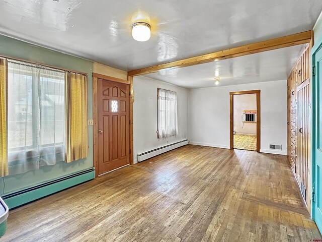 spare room with wooden walls, baseboard heating, and light hardwood / wood-style floors