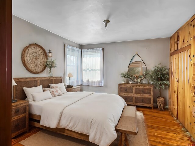 spare room with a baseboard radiator, a paneled ceiling, light hardwood / wood-style floors, wood walls, and a barn door