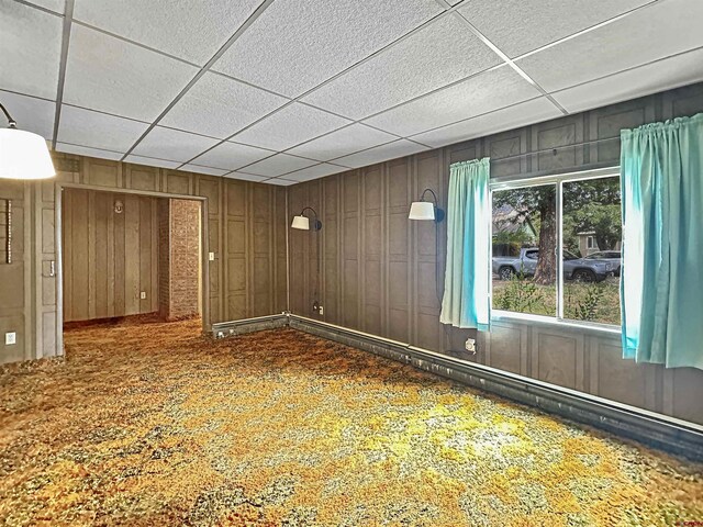 unfurnished room with wooden walls and a paneled ceiling