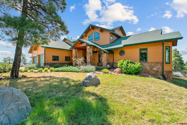 view of front of property with stone siding, an attached garage, and a front yard