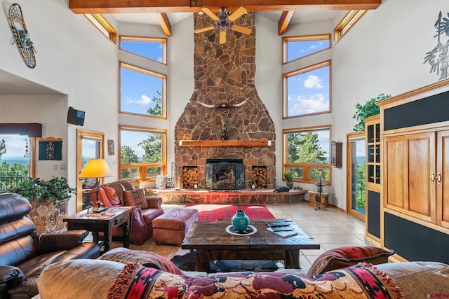 living area featuring a wealth of natural light, beam ceiling, a stone fireplace, and light tile patterned floors