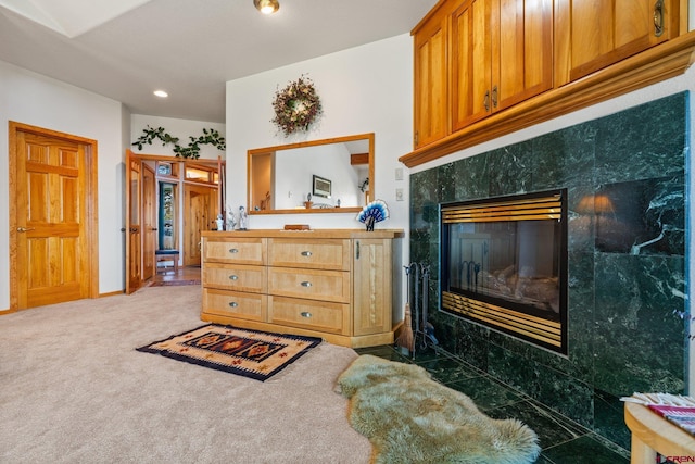 living area with a tiled fireplace, carpet, and baseboards