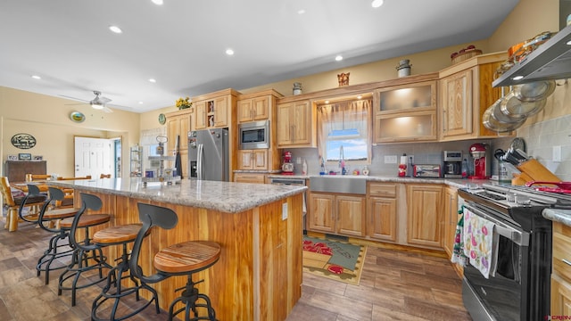37105 Ii Rd, Redvale, CO 81431 - kitchen with stainless steel appliances, wall chimney exhaust hood, a kitchen island, and decorative backsplash