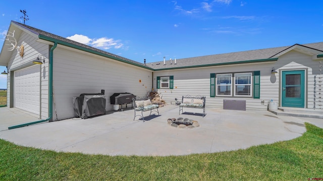 back of property featuring an attached garage, a patio area, and a fire pit