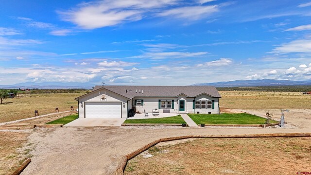 37105 Ii Rd, Redvale, CO 81431 - view of front facade featuring a garage, a mountain view, a front lawn, and concrete driveway