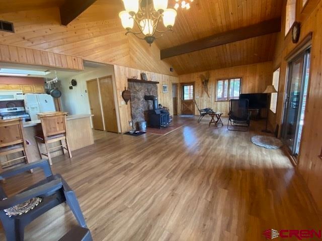 living room featuring wood ceiling, high vaulted ceiling, an inviting chandelier, beamed ceiling, and wood-type flooring