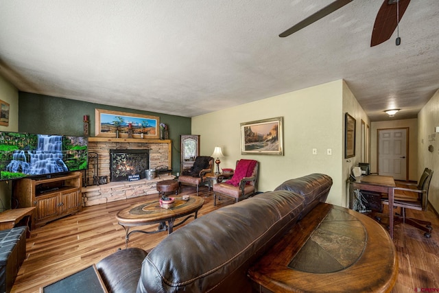 living room featuring a textured ceiling, a fireplace, hardwood / wood-style floors, and ceiling fan