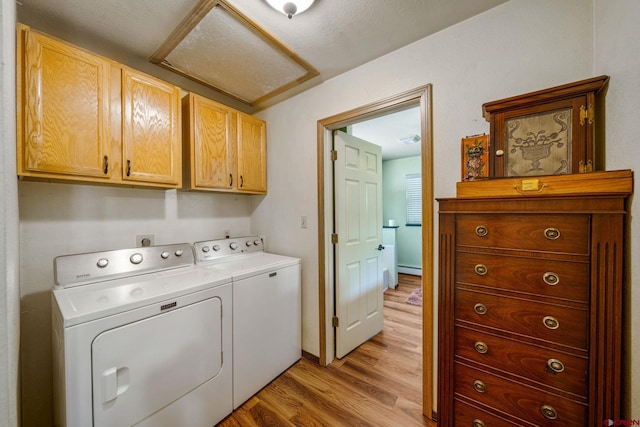 washroom with cabinets, washing machine and clothes dryer, light hardwood / wood-style floors, and a baseboard radiator