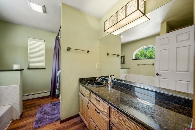 bathroom featuring a tub to relax in, vanity, hardwood / wood-style flooring, and baseboard heating