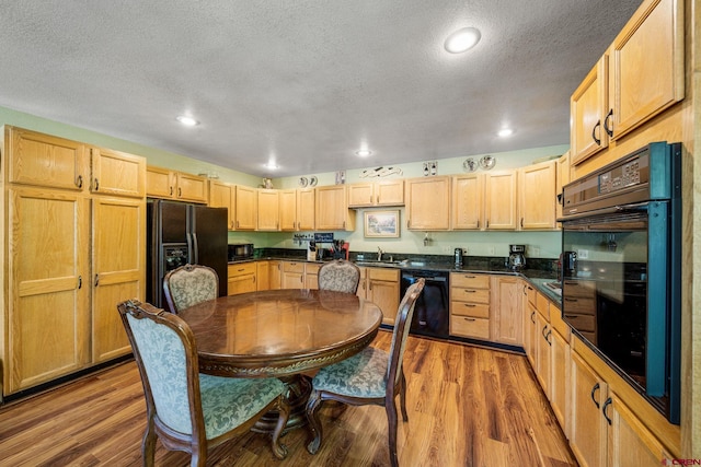 kitchen with light wood-type flooring, a textured ceiling, light brown cabinets, black appliances, and sink