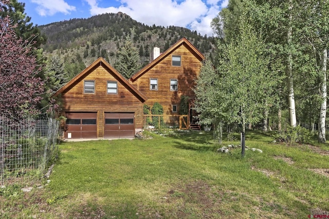 view of front of home featuring a garage, a chimney, an outdoor structure, a mountain view, and a front lawn