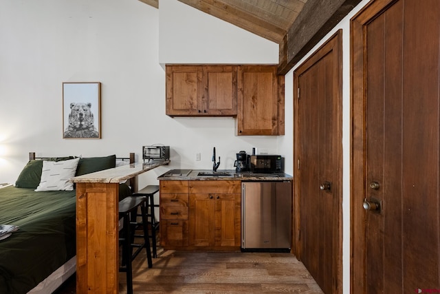 kitchen featuring sink, dark hardwood / wood-style flooring, kitchen peninsula, vaulted ceiling, and a breakfast bar