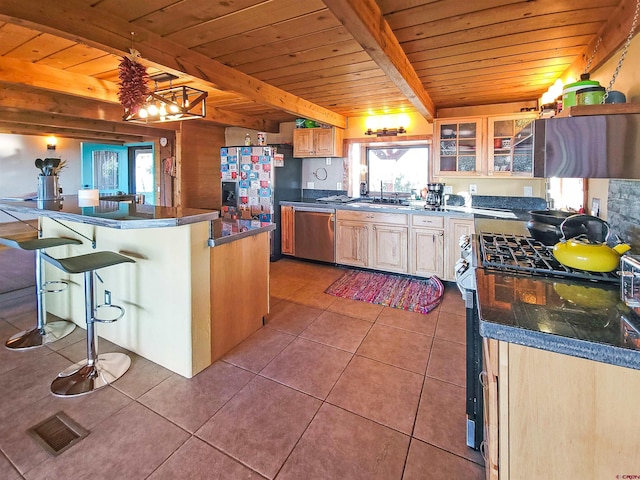 kitchen with plenty of natural light, beamed ceiling, appliances with stainless steel finishes, and light tile patterned floors