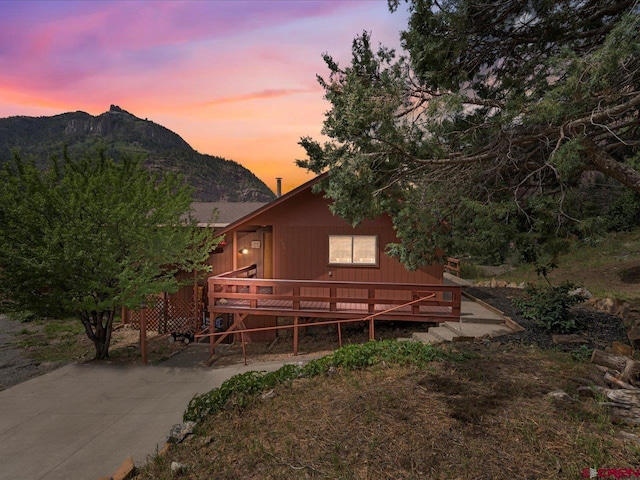 back house at dusk with a deck with mountain view