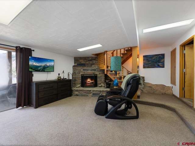 living area featuring carpet, stairs, and a stone fireplace