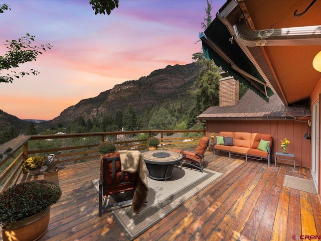 deck at dusk with an outdoor living space with a fire pit and a mountain view