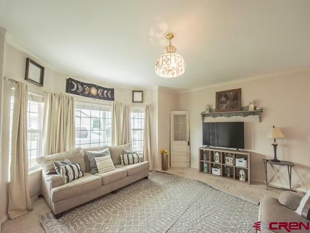 living room featuring carpet, an inviting chandelier, and ornamental molding