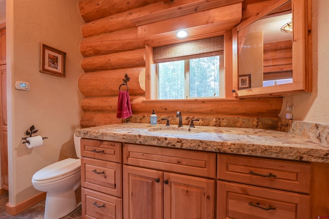 bathroom featuring tile patterned flooring, toilet, rustic walls, and vanity