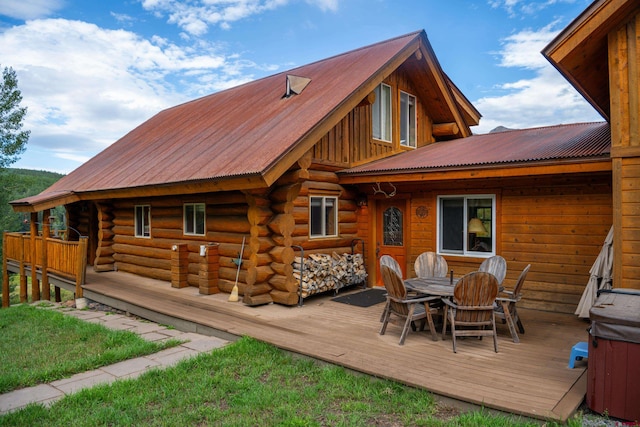 rear view of house with a hot tub and a deck