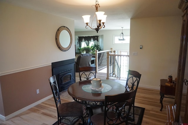 dining area with light hardwood / wood-style flooring, a wood stove, and a chandelier