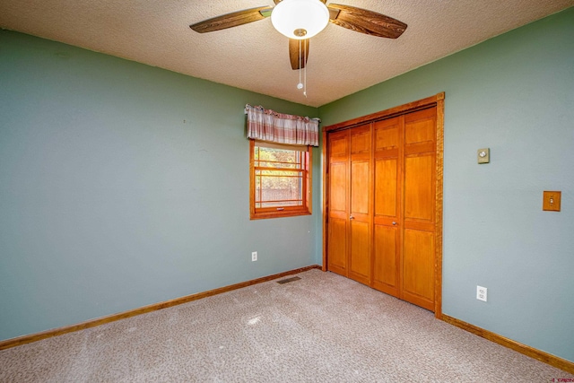 unfurnished bedroom featuring ceiling fan, a closet, light colored carpet, and a textured ceiling