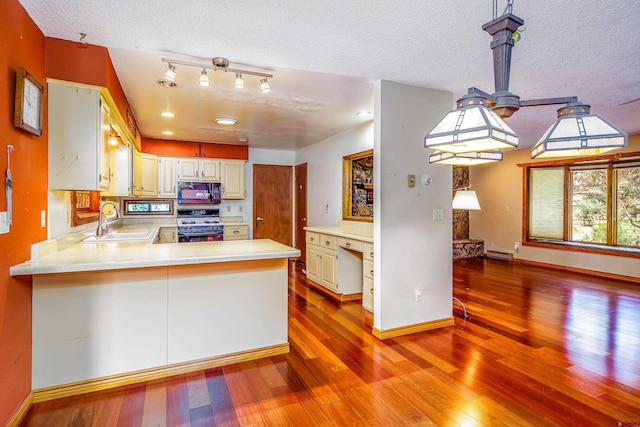 kitchen with sink, light wood-type flooring, a textured ceiling, range with gas stovetop, and kitchen peninsula