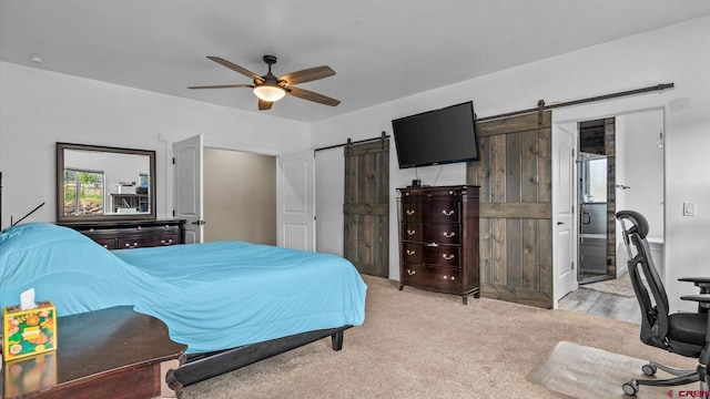 carpeted bedroom featuring ceiling fan, connected bathroom, and a barn door