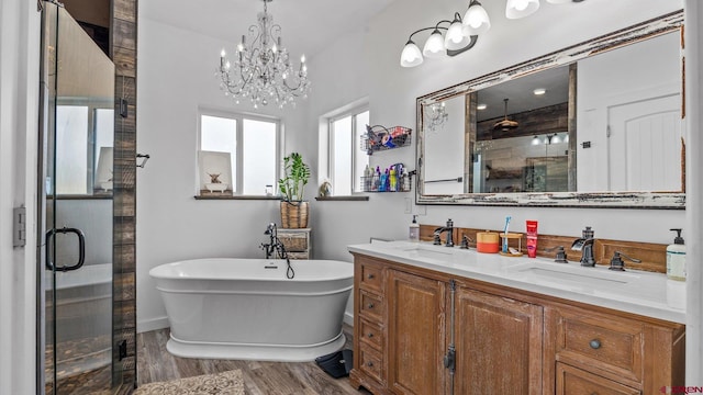 bathroom with double vanity, hardwood / wood-style floors, a chandelier, and a bathing tub