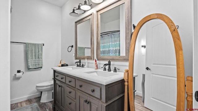 bathroom featuring toilet, double sink vanity, and wood-type flooring