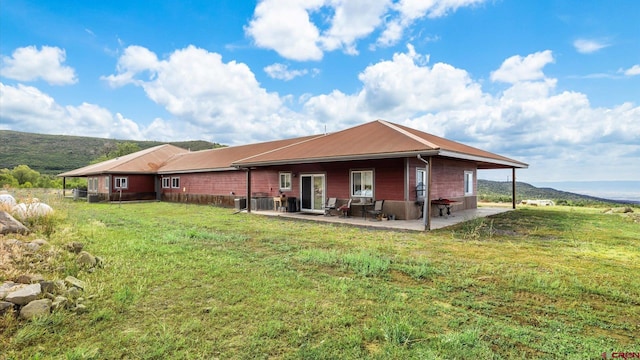 back of property with a patio, central AC, and a lawn