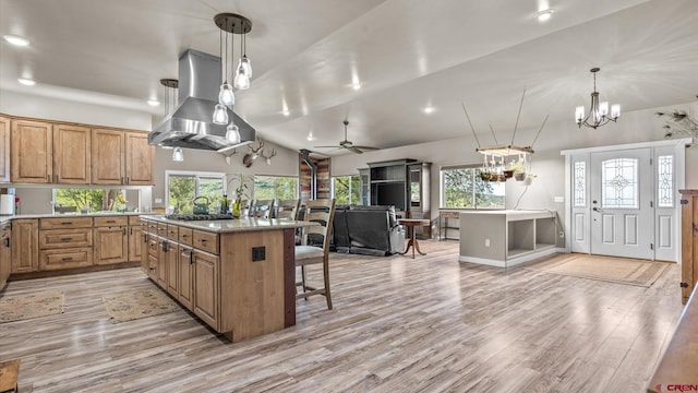 kitchen featuring light wood-type flooring, island exhaust hood, ceiling fan with notable chandelier, decorative light fixtures, and a breakfast bar area