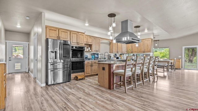 kitchen featuring plenty of natural light, island range hood, light wood-type flooring, and stainless steel refrigerator with ice dispenser