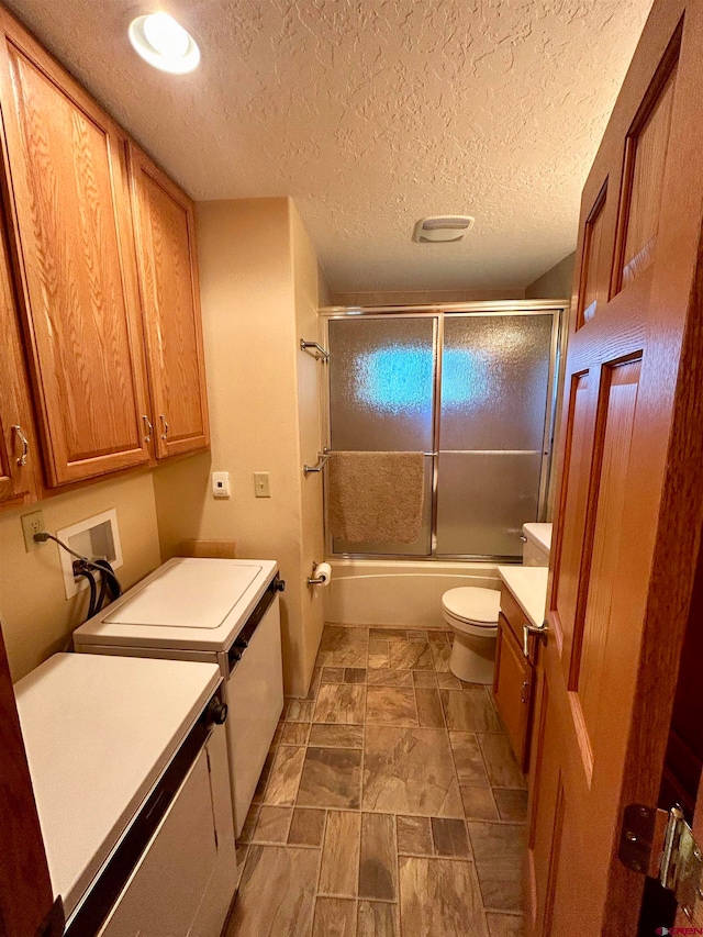 full bathroom with vanity, tile patterned flooring, bath / shower combo with glass door, a textured ceiling, and toilet