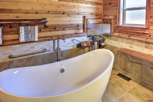 bathroom with stone finish floor, visible vents, and a freestanding bath