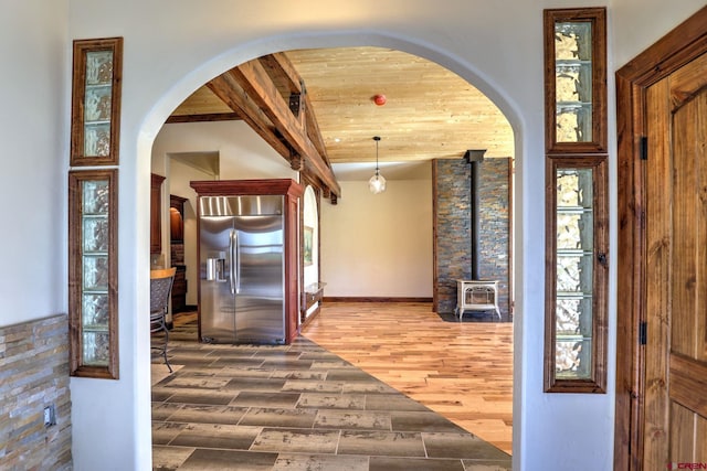 entrance foyer featuring baseboards, beam ceiling, arched walkways, and wood finished floors