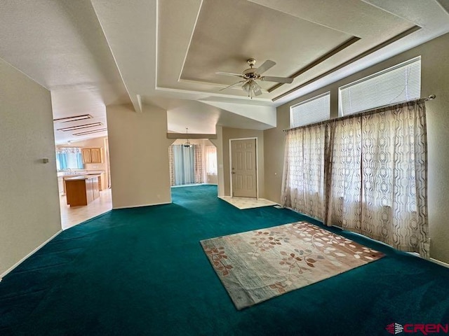 carpeted spare room with a tray ceiling and ceiling fan