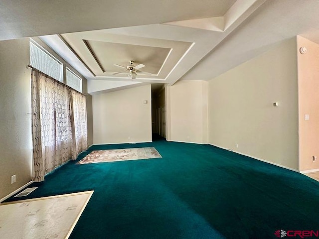 carpeted empty room with ceiling fan and a raised ceiling