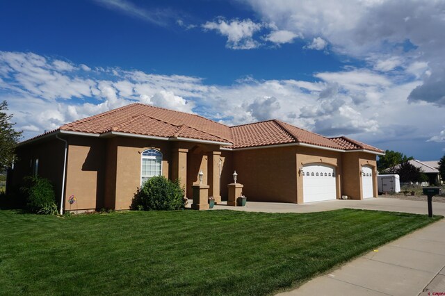 mediterranean / spanish home with a garage and a front lawn