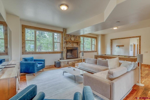 living room featuring a fireplace, light wood-type flooring, and plenty of natural light