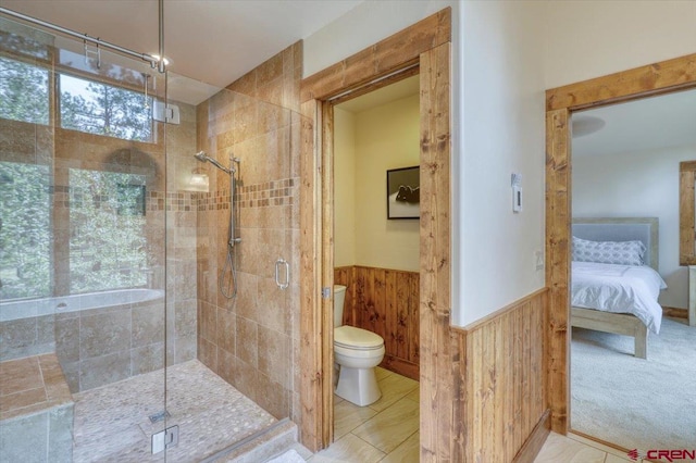 bathroom with a shower with door, toilet, and tile patterned flooring