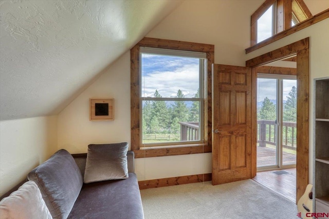 carpeted living room featuring a textured ceiling, plenty of natural light, and vaulted ceiling