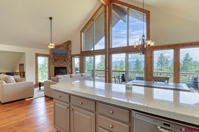 kitchen featuring high vaulted ceiling, a fireplace, light stone countertops, light hardwood / wood-style floors, and dishwasher