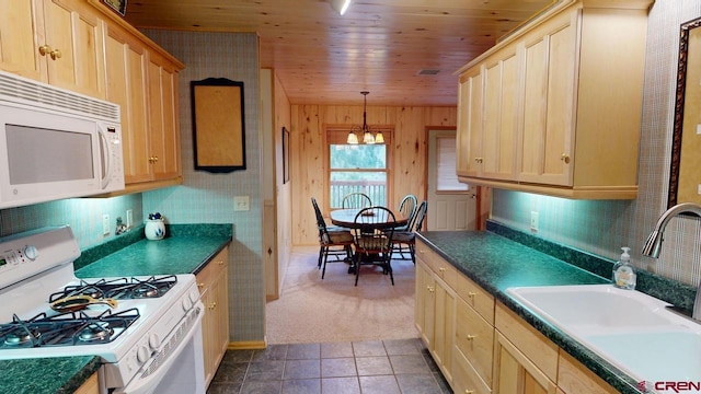 kitchen with sink, dark colored carpet, white appliances, wooden ceiling, and wooden walls