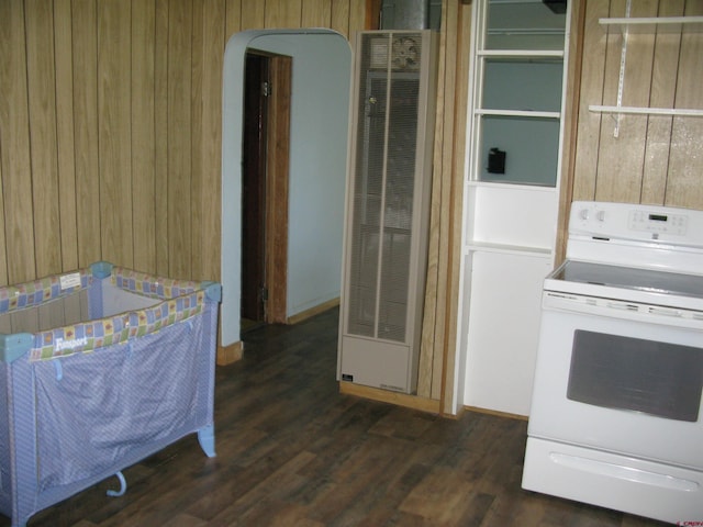 interior space with a heating unit, wooden walls, arched walkways, and dark wood finished floors