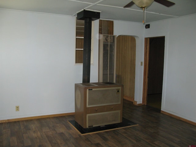 unfurnished living room featuring a wood stove, ceiling fan, baseboards, and wood finished floors