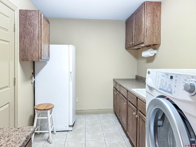 washroom featuring washer / dryer, cabinets, and light tile patterned flooring