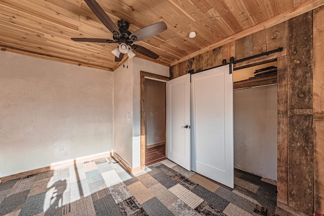 unfurnished bedroom with ceiling fan, a closet, wooden ceiling, a barn door, and carpet floors