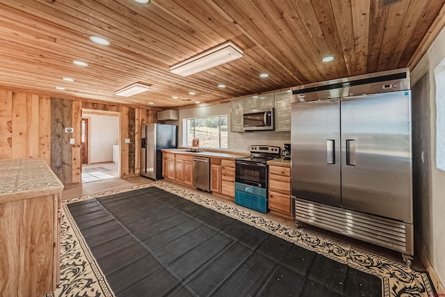 kitchen featuring wooden ceiling, light tile patterned floors, appliances with stainless steel finishes, sink, and wooden walls